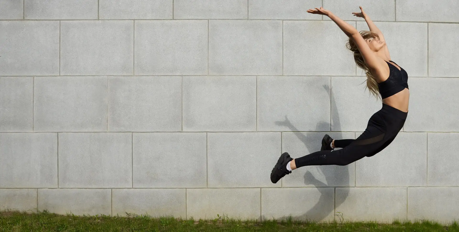 Athlete leaping mid-air against a concrete wall, sports physical therapy in Boca Raton for athletes and active adults